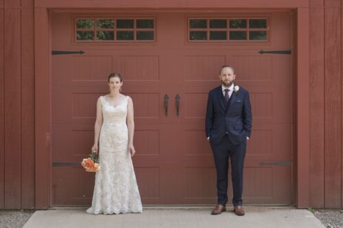 A bride and a groom stand in front of a red barn at the Publick House in Sturbridge, photographed by Spagnolo Photography as part of their micro-wedding photography package