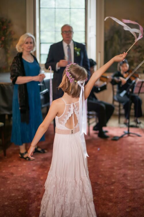 A flower girl waives a ribbon at guests at a King's Chapel micro-wedding reception in Boston, photographed by Spagnolo Photography as part of a package
